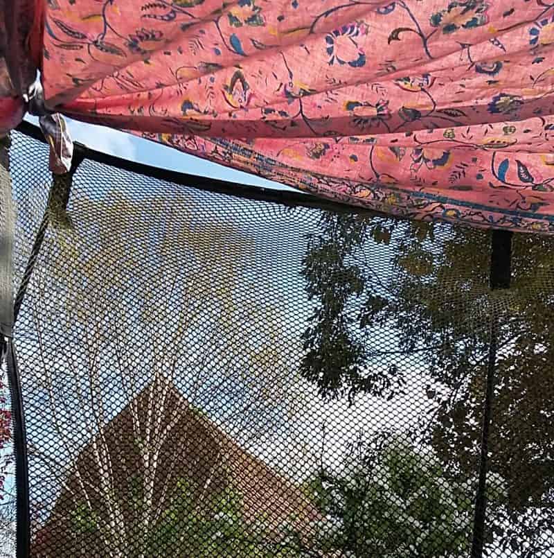 Picture looking out from the play tent we made on the trampoline, with bedspreads clipped to the top of the net.