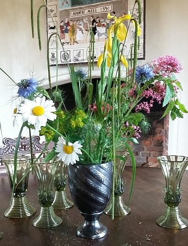 Picture of a bunch of flowers in on a table inside Bourne Mill, a National Trust property we visited on a frugal trip