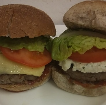 A close up picture of two beefburgers made with frugal yellow-stickered ingredients, one with cheddar and one with boursin