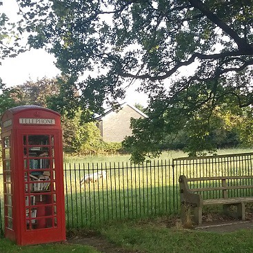 Picture of the telephone box and bench by the main street field. Activities for children should be considered when moving to the country.