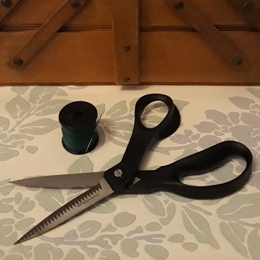 Picture of scissors and thread by a sewing box