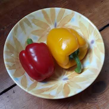Picture of a red and yellow pepper in a yellow bowl for my post on Plastic Free July on a budget